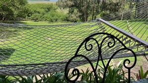 A hammock with a metal frame, a brick wall, and green plants. - Minutos a Jose Ignacio, La Casita De Infinita, en el campo, cerca la playa! (Faro de José Ignacio)