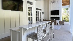 Una cocina moderna con encimera blanca, asientos tipo barra y un ventilador de techo.
