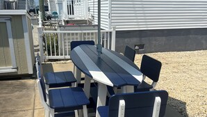 Un patio con mesa y sillas, un paraguas y una casa al fondo.