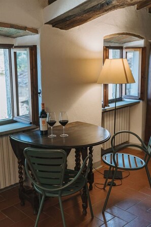 Un área de comedor con una mesa redonda, dos sillas, una botella de vino y dos copas de vino.