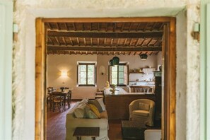 Um interior rústico com área de refeições, um sofá e uma cozinha.