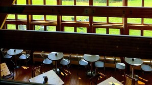 A dining area with tables and chairs, large windows with a view of green landscape and mountains. - NewVida Preserve (Jay)