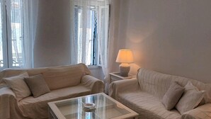 A minimalist living room with two sofas, a glass coffee table, and a lamp. - A fully air con 2-bedroom apartment,a cosy living room,fully equipped kitchen. (Tinos)