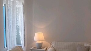 A cozy living room with two sofas, a glass-top coffee table, and a lamp on a side table. - A fully air con 2-bedroom apartment,a cosy living room,fully equipped kitchen. (Tinos)