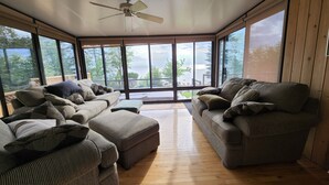 A sunroom with a ceiling fan, large windows, and a view of the outdoors.