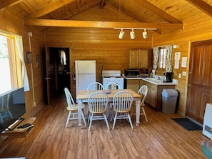 Cozy cabin with a fully equipped kitchen, dining area, and comfortable seating for four.