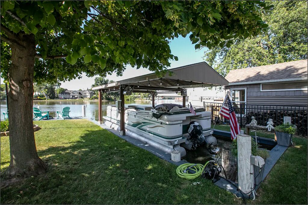 Un espace abrité où sont entreposés des bateaux, avec un bateau visible, un drapeau américain et une maison en arrière-plan.