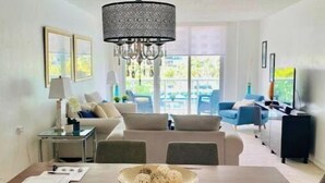 Comedor con mesa de madera, sillas, una lámpara de araña y vistas al exterior.