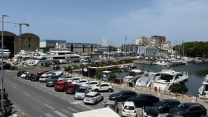 A marina with parked cars and yachts, a Ferris wheel in the background, and buildings along the waterfront. - Beautiful flat on the second floor with lift with beautiful modern fittings and large windows with a splendid view of the Viareggio dock just a few minutes' walk from the promenadeand beach.Elegantly furnished it consists of a living room with modern wal (Viareggio)