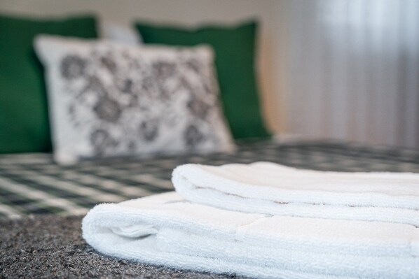 A neatly folded white towel on a textured bedspread.