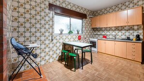 Eine kleine Küche mit Essbereich, ausgestattet mit einem Fenster, Holzschränken und einer gefliesten Spritzschutzwand.