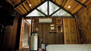 A wooden cabin with a sloped roof, a bed, a kitchenette, and a bathroom with a shower. - Wilderness Treehouse Above a Stunning Waterfall (Tambon Pa Miang)