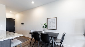 A modern dining area with a granite countertop, four black chairs, and a table.
