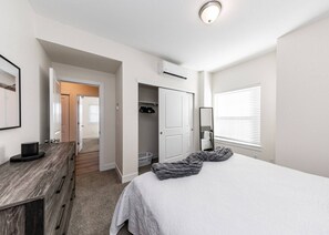 Un dormitorio con cama, cómoda, vestidor y ventana con persianas.