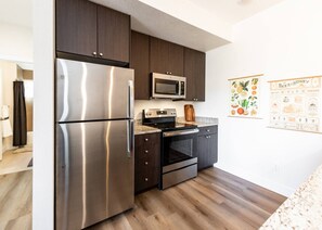 Una cocina moderna con electrodomésticos de acero inoxidable, armarios oscuros y piso de madera.