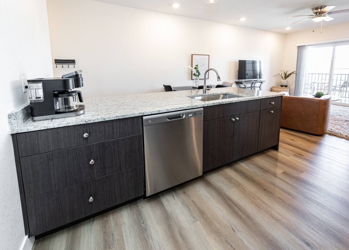 A modern kitchen with a dishwasher, a coffee maker, and a sink.