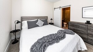 A modern bedroom with a bed, bedside tables, a wardrobe, and a shower area.