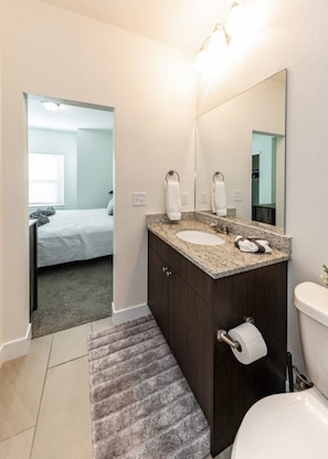 A bathroom with a sink, mirror, toilet, and a bed visible in the adjacent room. - 2 Bed 2 Bath Near Garden of the Gods Near Nature (Colorado Springs)