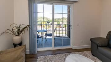 A living room with a sliding glass door leading to an outdoor patio with a table and chairs.