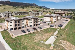 A residential area with multi-story apartment buildings, a parking lot, and a hilly landscape in the background. - 2 Bed 2 Bath Near Garden of the Gods Near Nature (Colorado Springs)