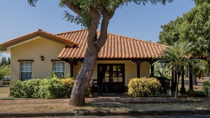 A two-story house with a tiled roof, a front porch, and a small garden area. - Casa de Amor B-58                                                             . (Villa El Carmen)