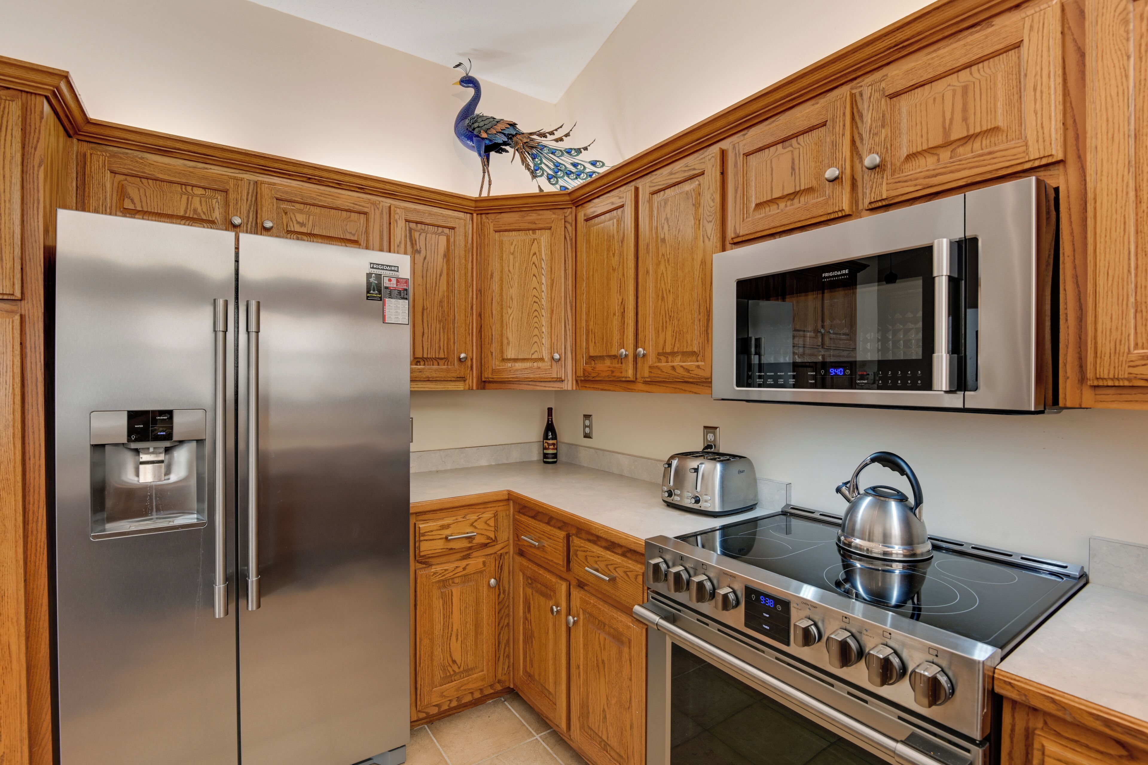 A modern kitchen with wooden cabinets, stainless steel appliances, a water dispenser, a microwave, a stove, and a toaster.