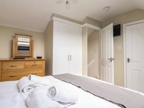 Ein Schlafzimmer mit einem Bett, einem Holzschrank, einem Spiegel und einem Kleiderschrank.