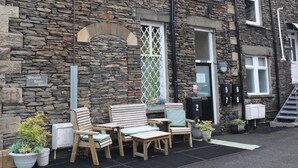 A stone building with a sign reading "Wansfell Tower Court." There are outdoor seating areas with wooden furniture and potted plants.