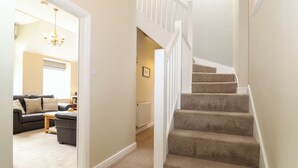 A staircase with carpeted steps and white railings, leading to an upper floor.