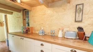 A kitchen with white cabinets, a wooden countertop, a kettle, a toaster, and a knife block.