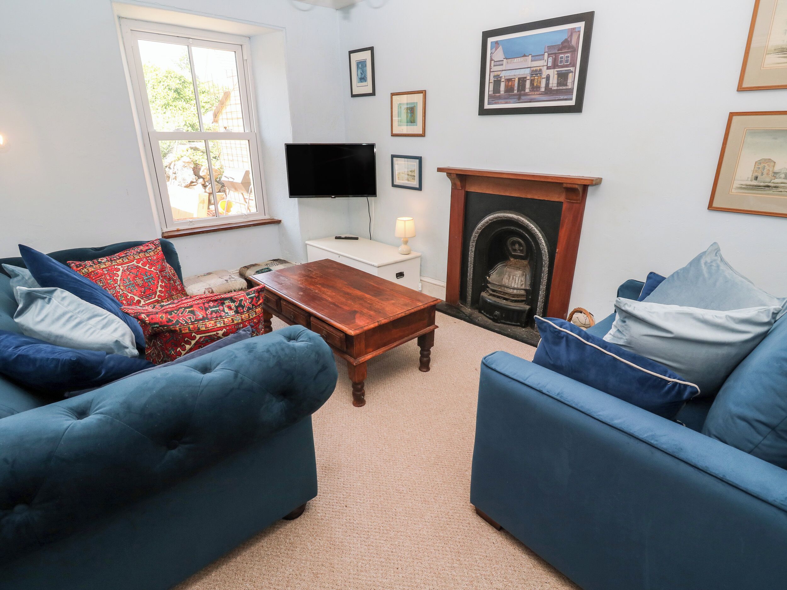 Ein Wohnzimmer mit zwei blauen Sofas, einem Holztisch, einem Fernseher, einem Kamin und gerahmten Bildern an der Wand.