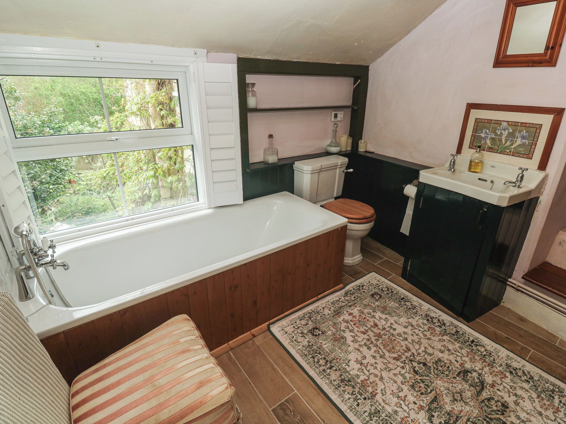 A bathroom with a bathtub, toilet, sink, and a window.