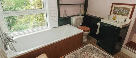 A bathroom with a bathtub, toilet, sink, and a window.