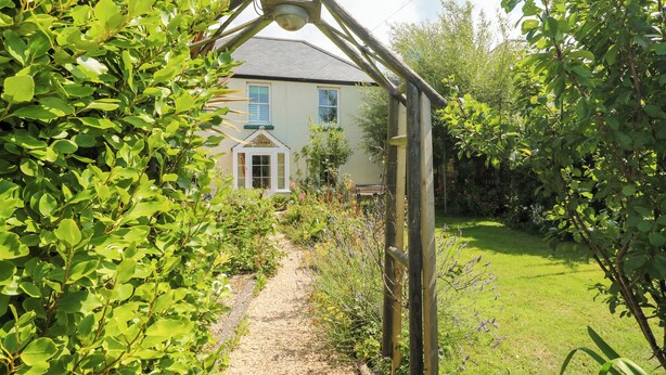 A garden path leading to a house with a white door and windows.