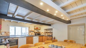 A kitchen with wooden cabinets, a dining table, and a built-in oven. - Clifford House Farm (Skipton)