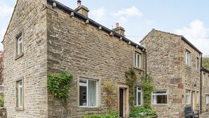 A stone building with a traditional design, featuring a small porch and a window with a curtain. - Clifford House Farm (Skipton)