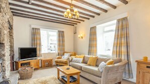 A cozy living room with a sofa, a TV, and a fireplace. - Clifford House Farm (Skipton)