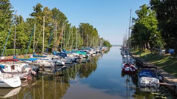 A marina with boats docked along a calm waterway, surrounded by trees and a grassy area.