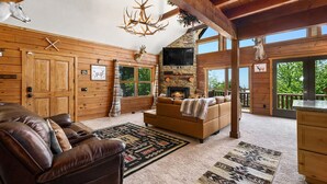L’intérieur d’une cabane en rondins, avec une cheminée, un canapé en cuir et des décorations en forme de bois de cerf.
