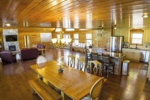 A spacious living area with a wooden ceiling, a fireplace, a dining table, and a kitchen area. - SPACIOUS Lakeside Home in the perfect LOCATION near all the action! (LaFollette)