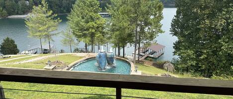 A swimming pool with a slide, surrounded by trees and a dock.