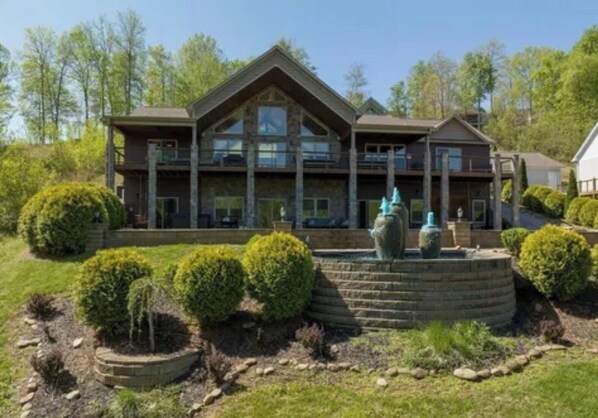 A large, multi-story building with a symmetrical facade, a central entrance, and a landscaped garden with a fountain.