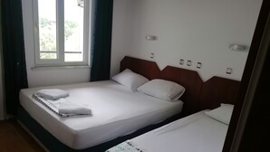 A hotel room with two single beds, a window with curtains, a wall-mounted air conditioner, and a door with a handle. - Pasa Restaurant & Pansiyon (Kemer)