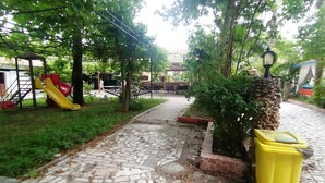 A park with a playground, a paved walkway, and a trash bin. - Pasa Restaurant & Pansiyon (Kemer)