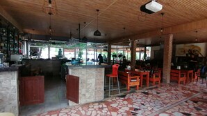 A restaurant with a tiled floor, wooden ceiling, and a bar area with bottles. - Pasa Restaurant & Pansiyon (Kemer)