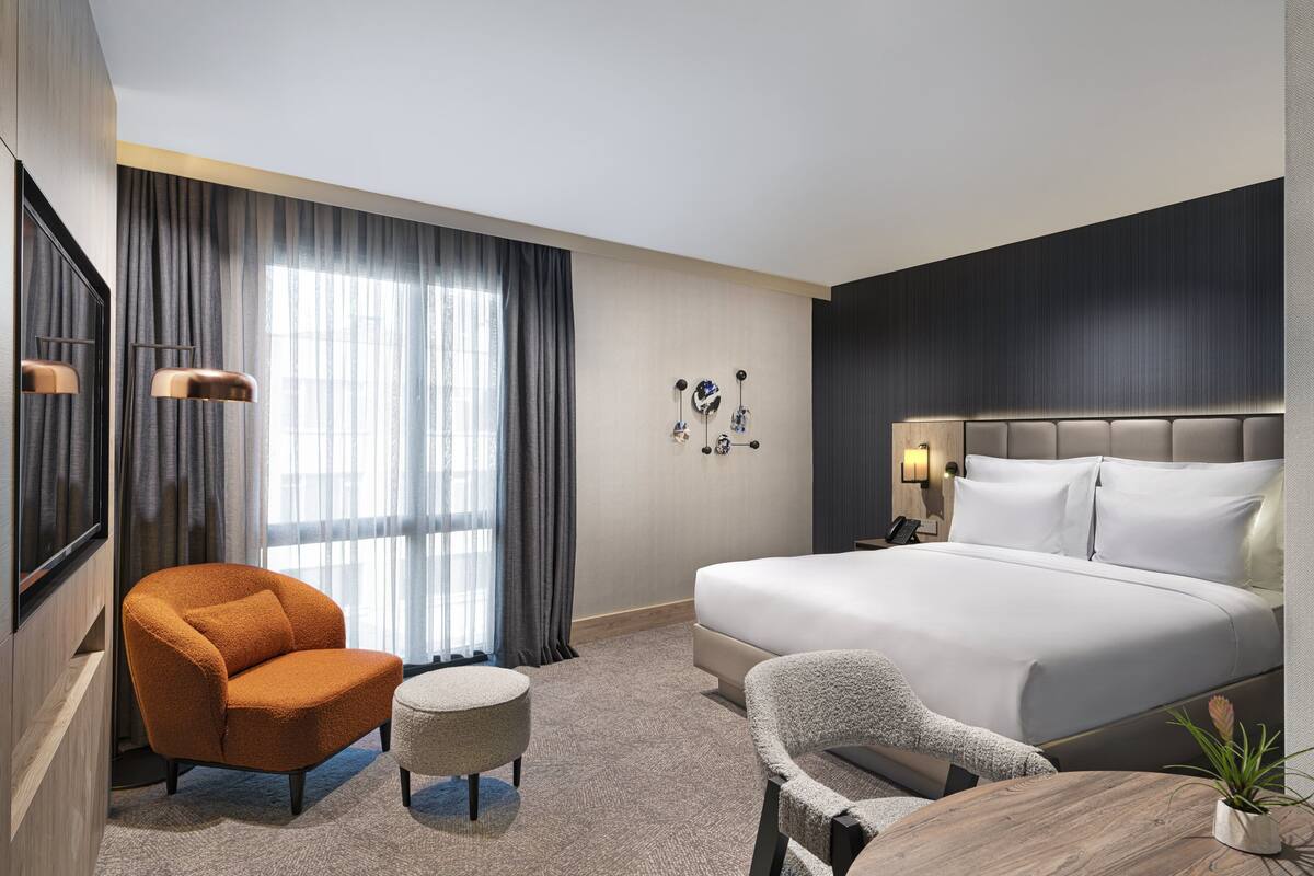 Une chambre d’hôtel avec un grand lit, un canapé, un fauteuil, une petite table et un téléviseur.
