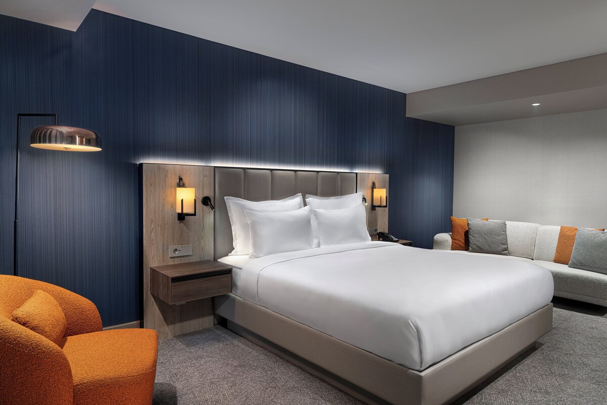 Een moderne hotelkamer met een groot bed, een nachtkastje, een lamp en een bank.