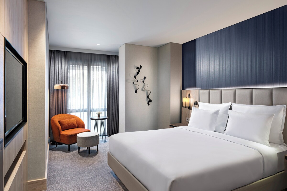 Een hotelkamer met een groot bed, een stoel, een klein tafeltje en een televisie.