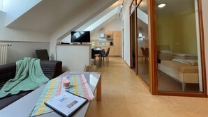 Un apartamento moderno con zona de estar tipo loft, kitchenette y un dormitorio con puerta de vidrio corredera.