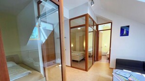 Un dormitorio moderno con una puerta de vidrio que da al baño, una cama y un escritorio con una silla.